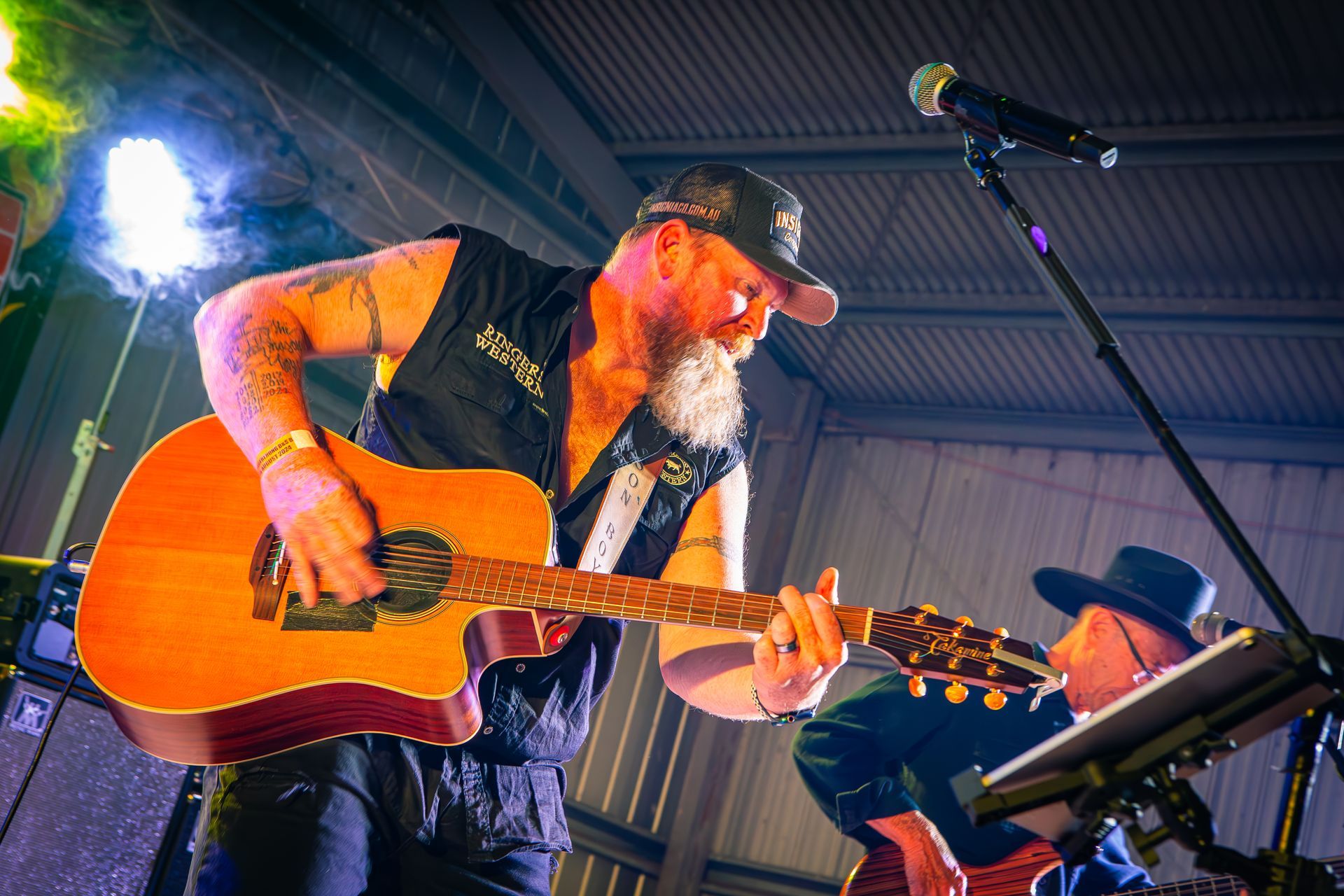 A man with a beard is playing a guitar and singing into a microphone