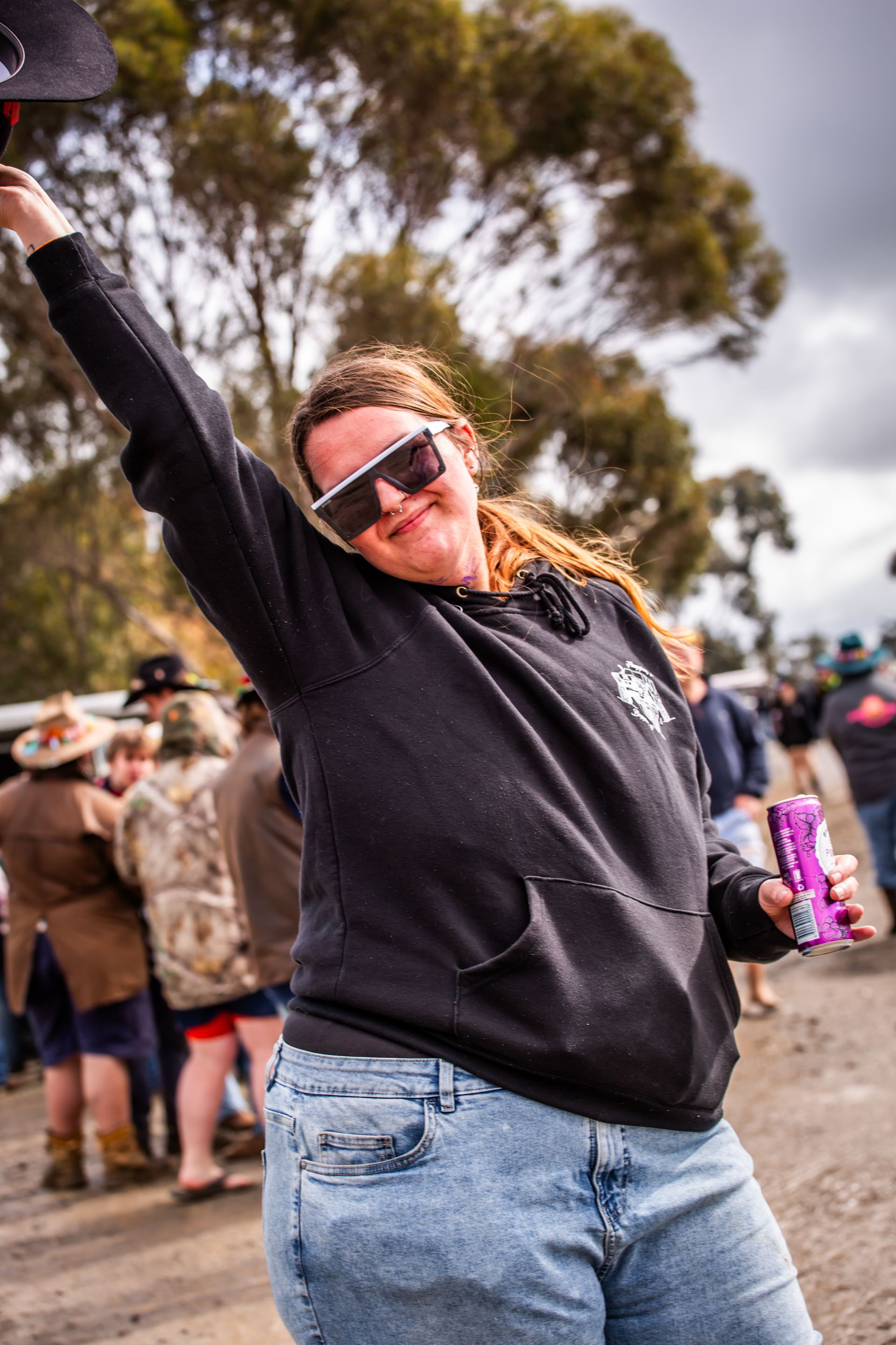 A woman wearing sunglasses and a black shirt is holding a purple can