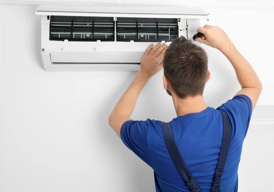 A man is fixing an air conditioner on a wall.