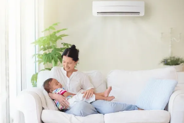 A woman is sitting on a couch holding a baby.