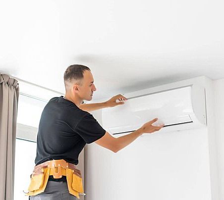 A man is installing an air conditioner on a wall.