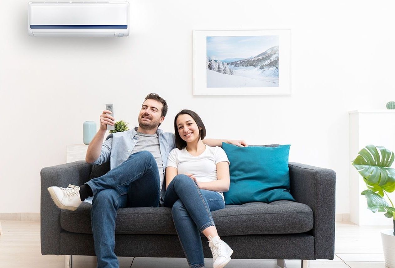 A man and a woman are sitting on a couch holding a remote control.