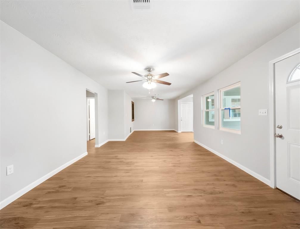 An empty living room with hardwood floors and a ceiling fan.