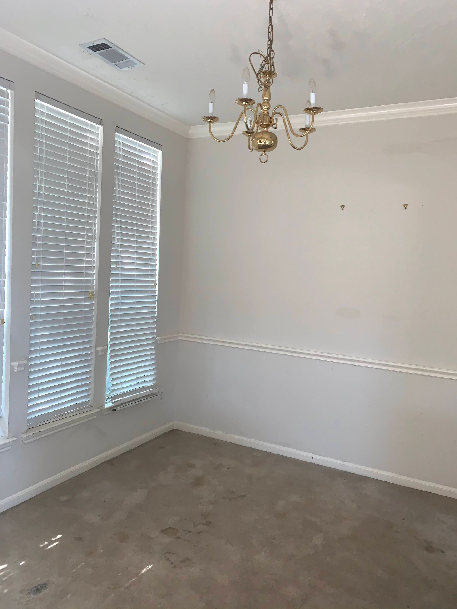 An empty dining room with a chandelier hanging from the ceiling.