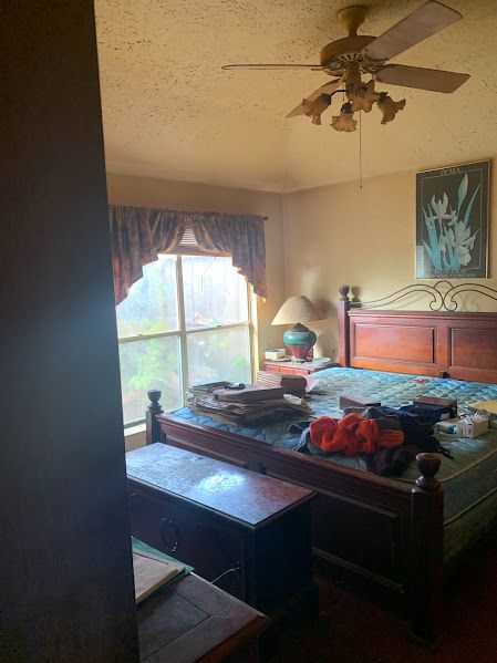 A bedroom with a bed and a ceiling fan.