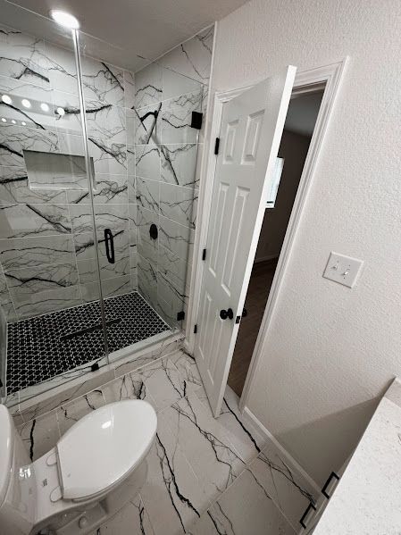 A bathroom with a toilet , shower , and door.