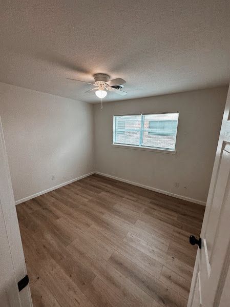 An empty bedroom with hardwood floors and a ceiling fan.