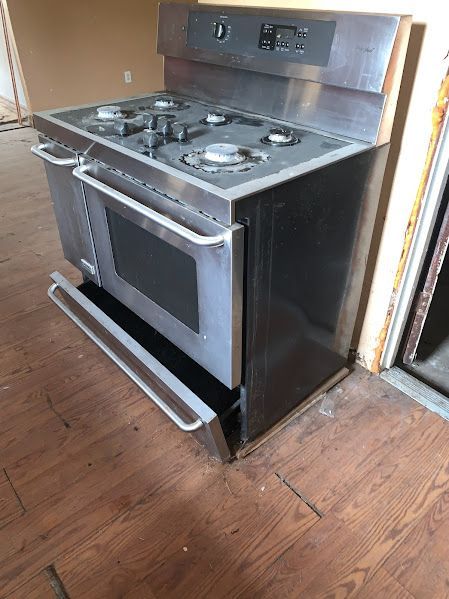A stainless steel stove is sitting on a wooden floor in a room.