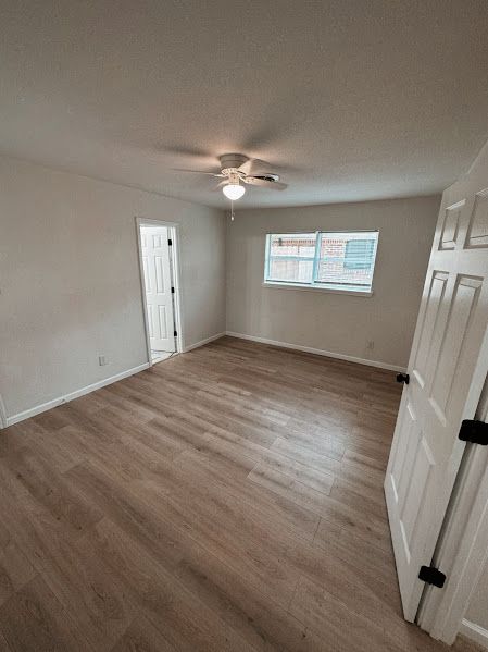 An empty bedroom with hardwood floors and a ceiling fan.