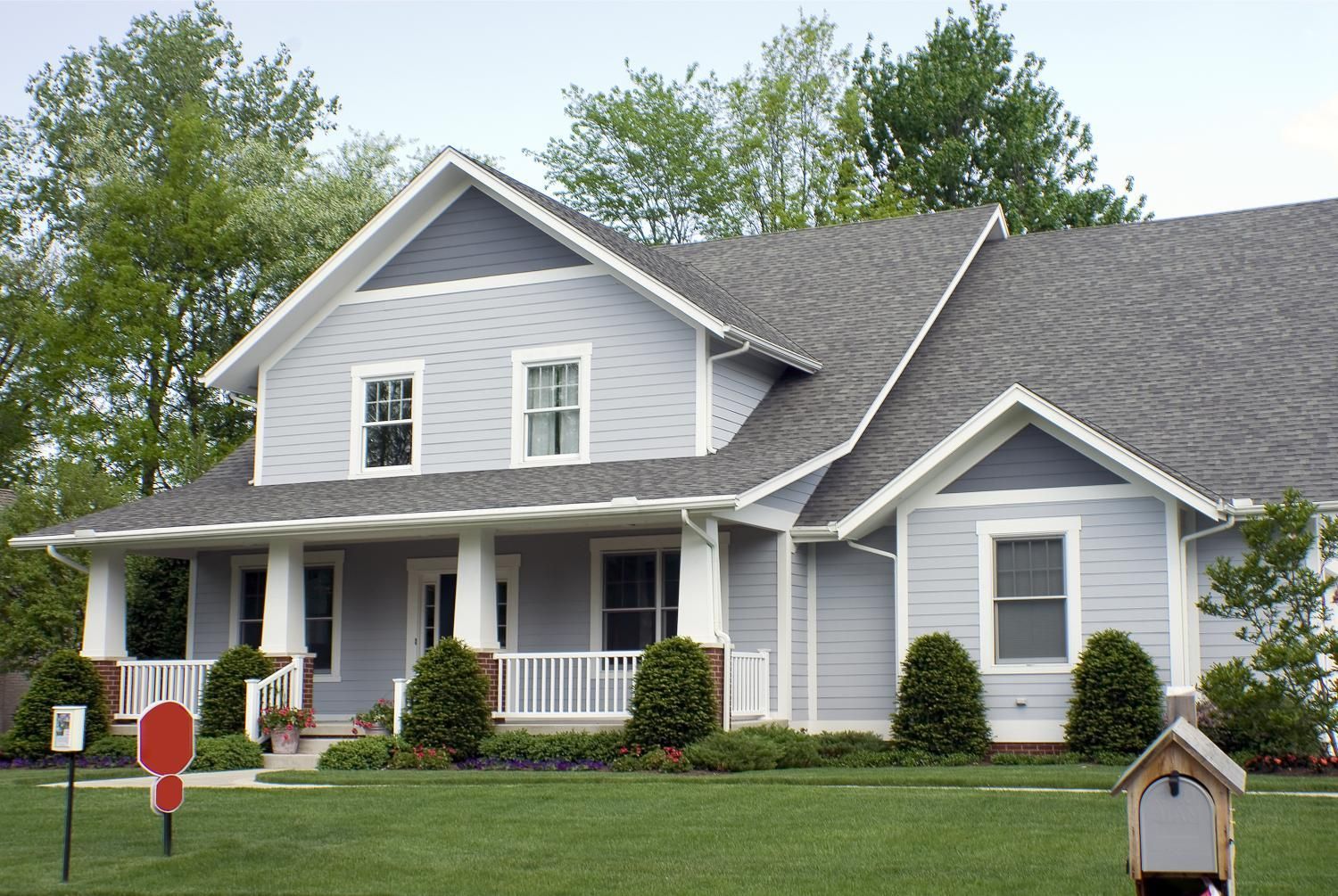 Blue and white two-story house with a porch and gray roof on a green lawn.
