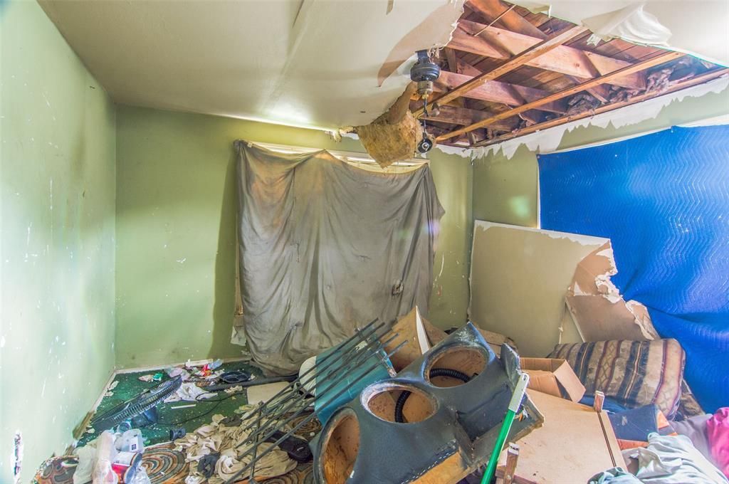 A room with a broken ceiling and a lot of trash on the floor.