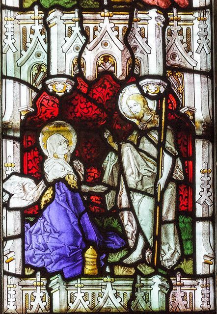 A stained glass window shows a man and a woman standing next to each other.