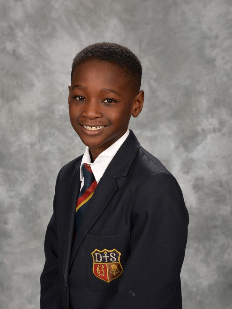 A young boy wearing a suit and tie with a dts logo on his pocket