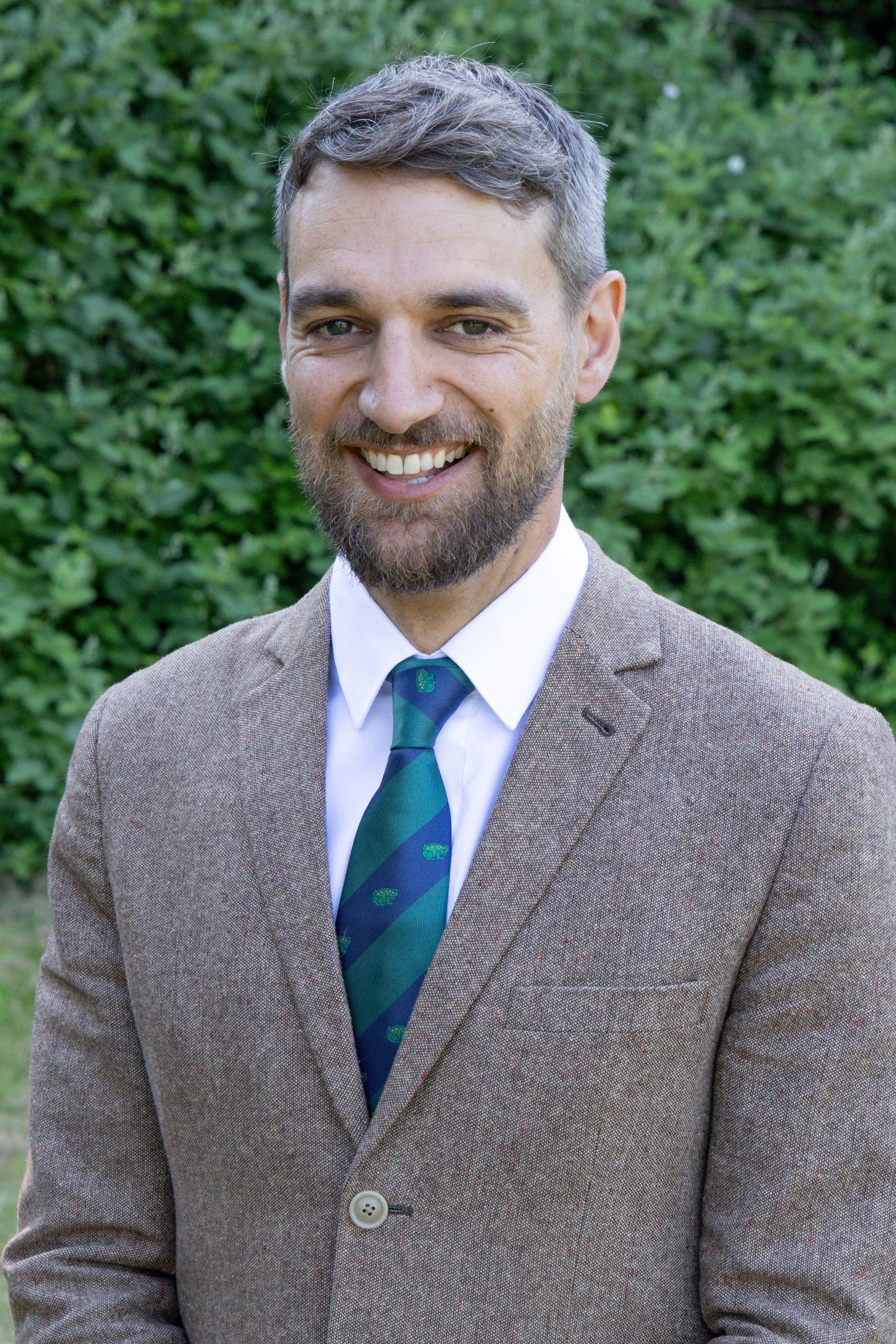 A man in a suit and tie is smiling for the camera.