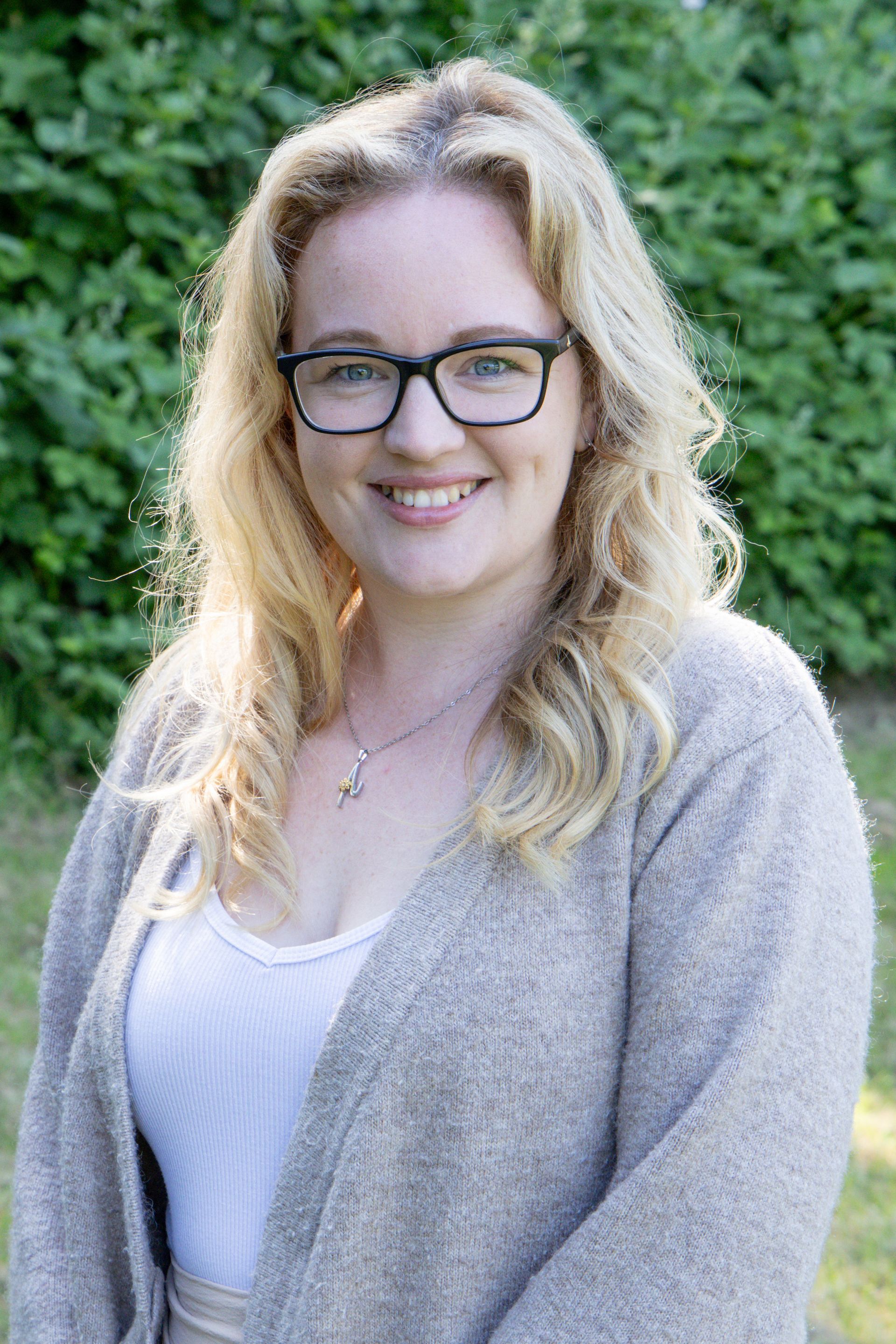A woman wearing glasses and a sweater is smiling for the camera.