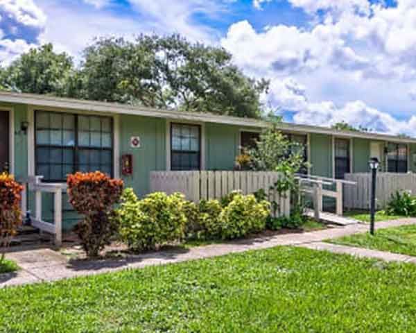 A green house with a white fence and a ramp in front of it.