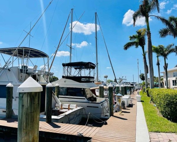 A row of boats are docked at a marina on a sunny day
