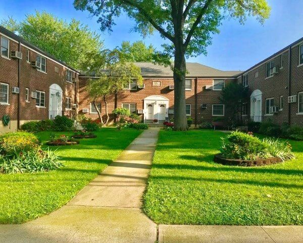 A brick apartment building with a tree in front of it