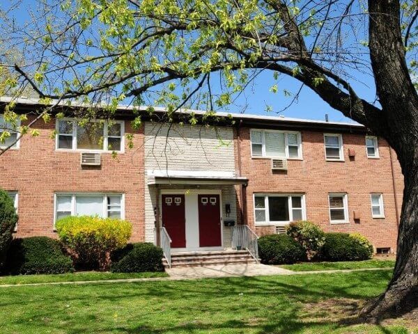 A brick apartment building with a tree in front of it