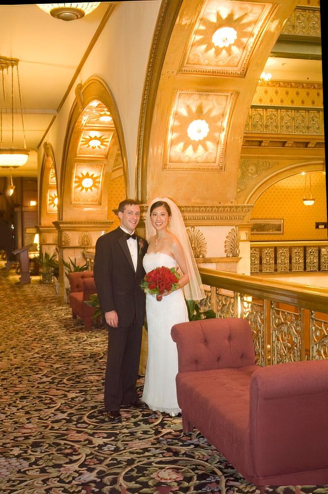 A bride and groom are posing for a picture in a hallway.