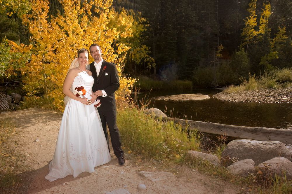 A bride and groom are posing for a picture in front of a river.
