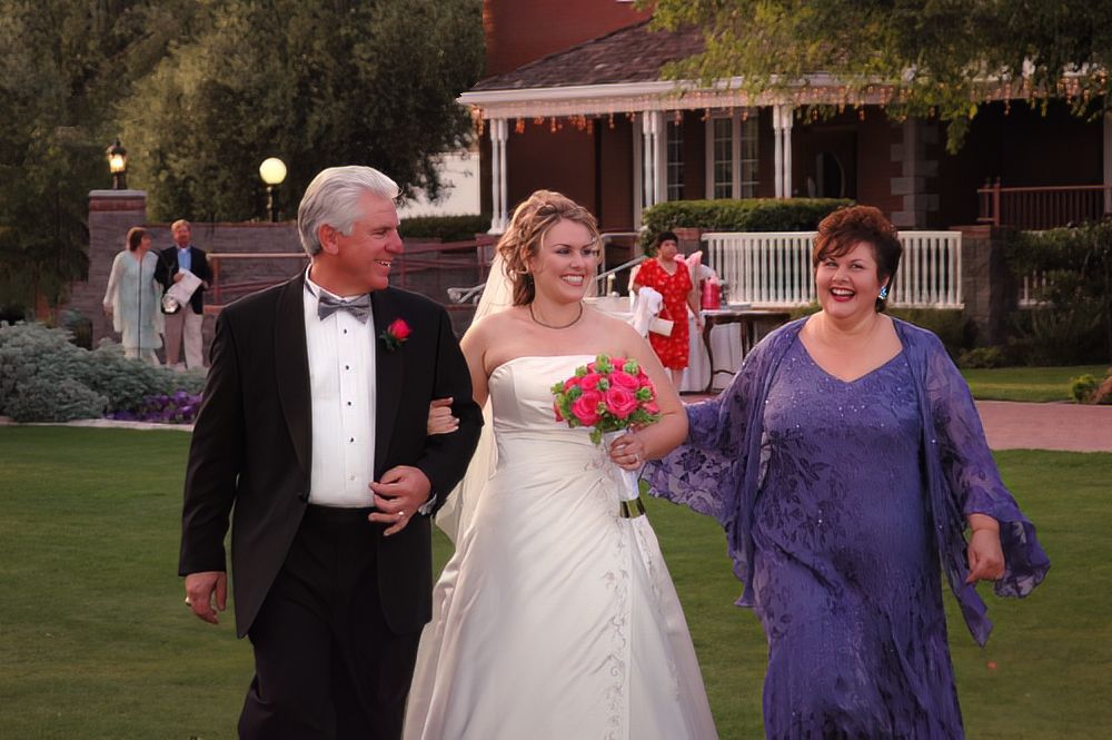 A bride is walking down the aisle with her parents