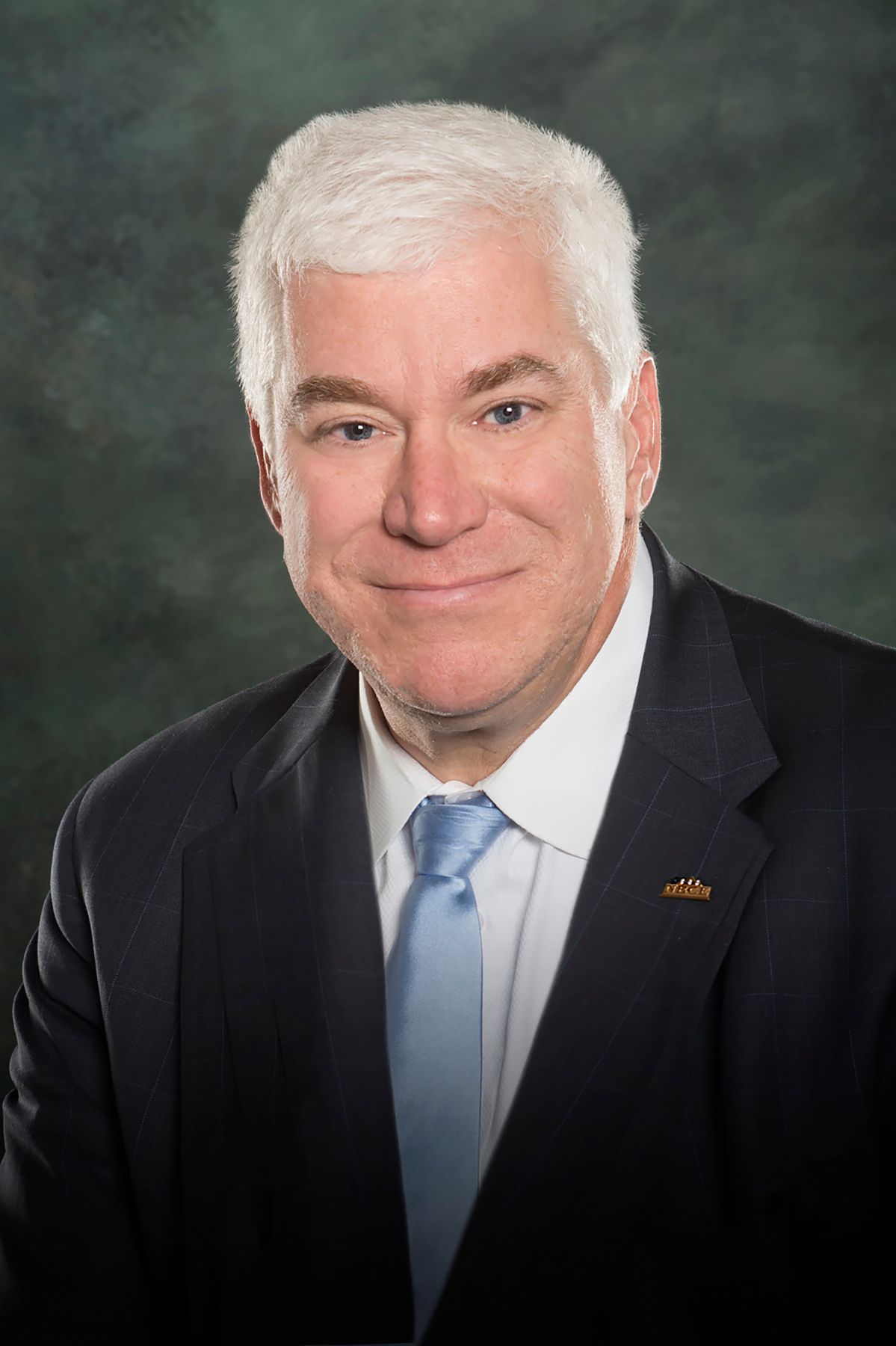 A man in a suit and tie is smiling for the camera.