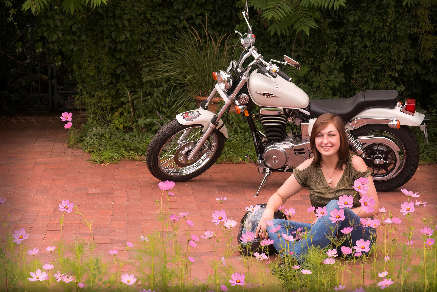 A woman is sitting on the ground next to a motorcycle.