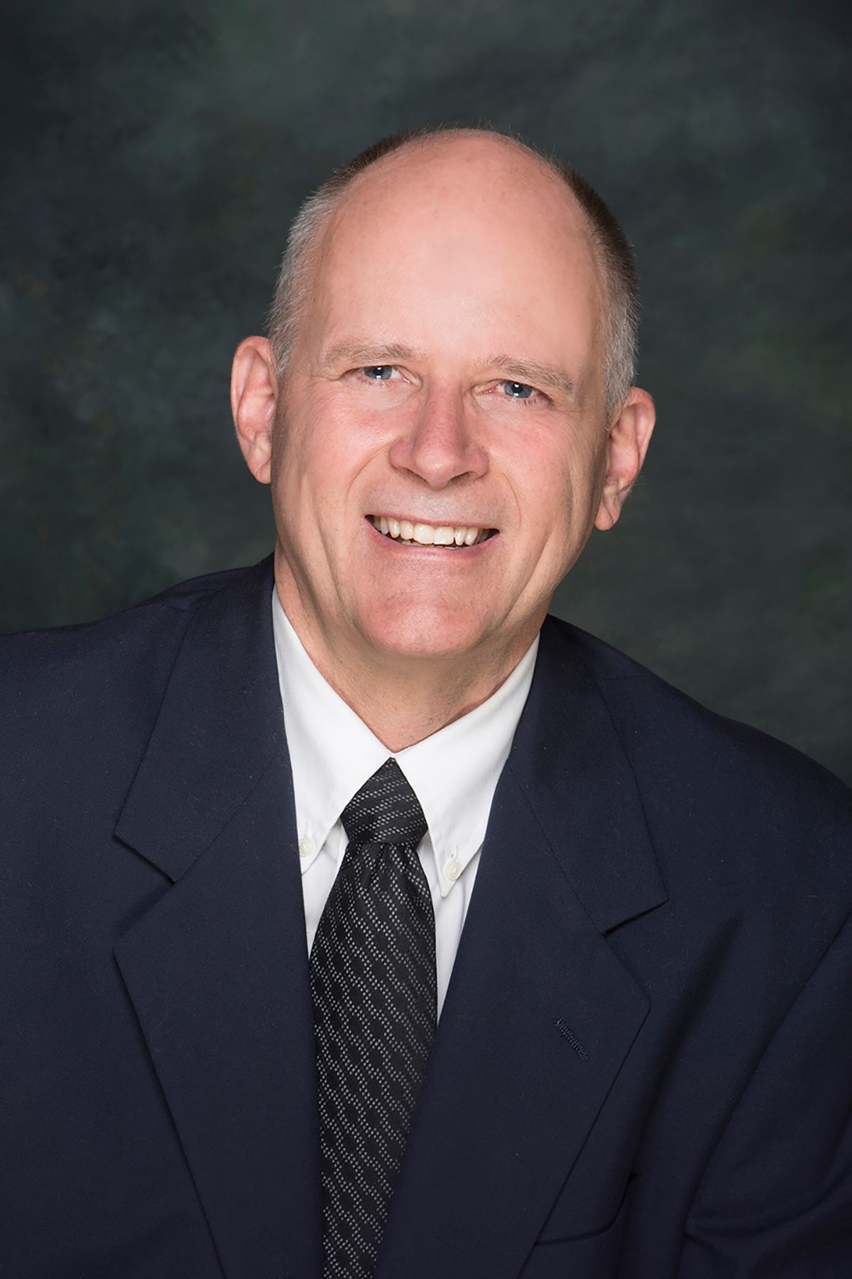 A man in a suit and tie is smiling for the camera.