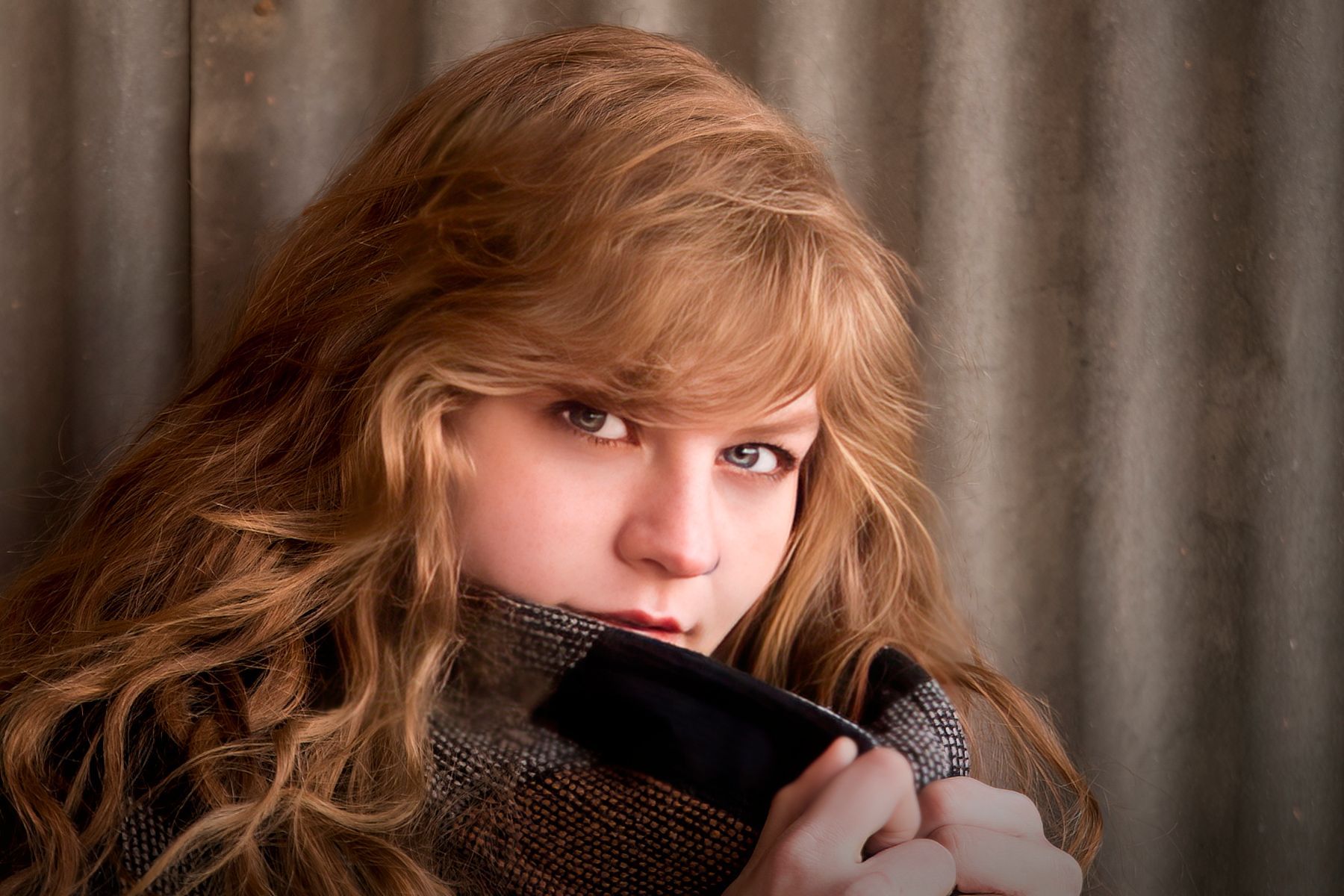 A woman with long red hair is wearing a scarf around her neck