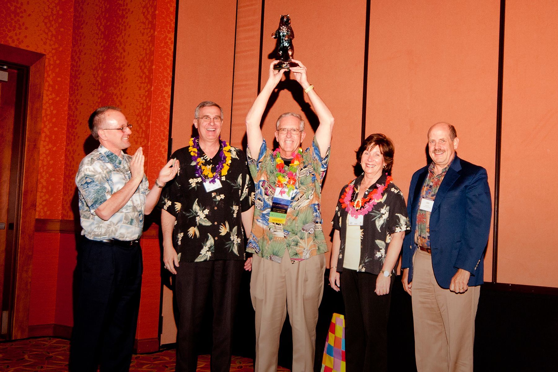 A group of people standing around a man holding a trophy