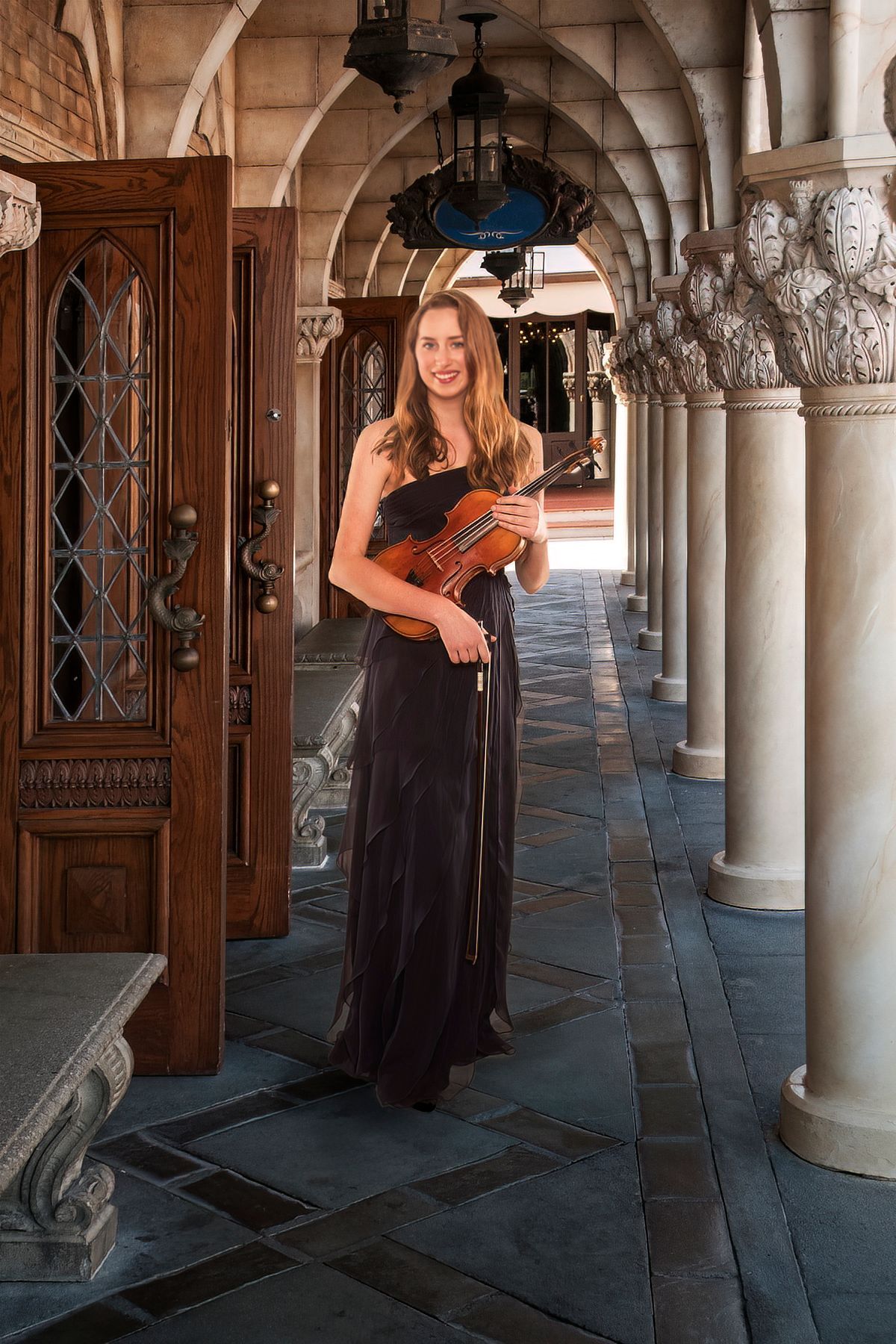A woman is standing in a hallway holding a violin.