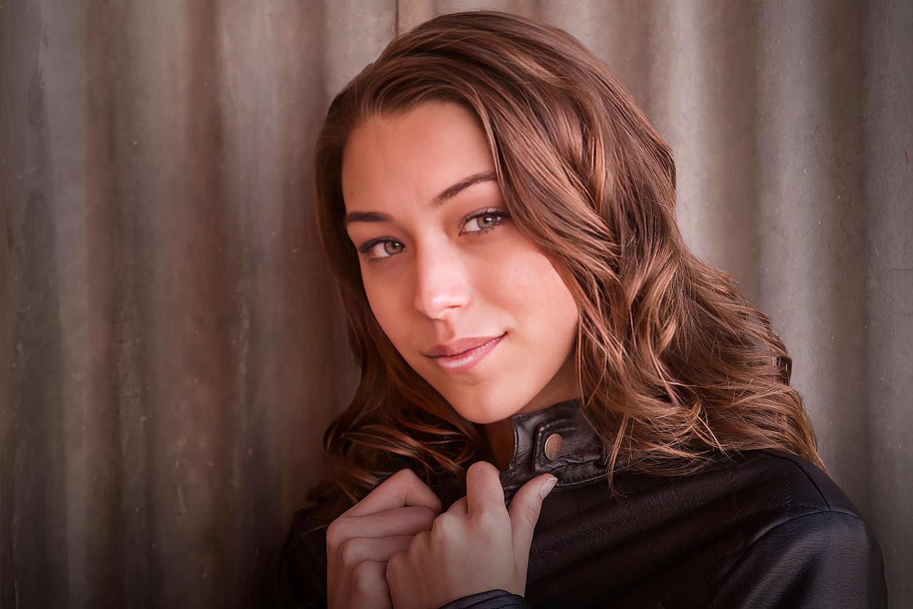 The woman is wearing a black jacket and looking at the camera.