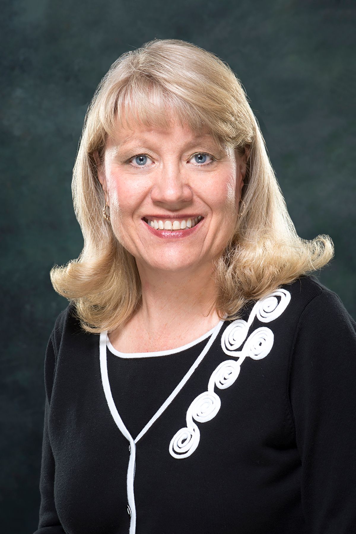 A woman in a black and white sweater is smiling for the camera.