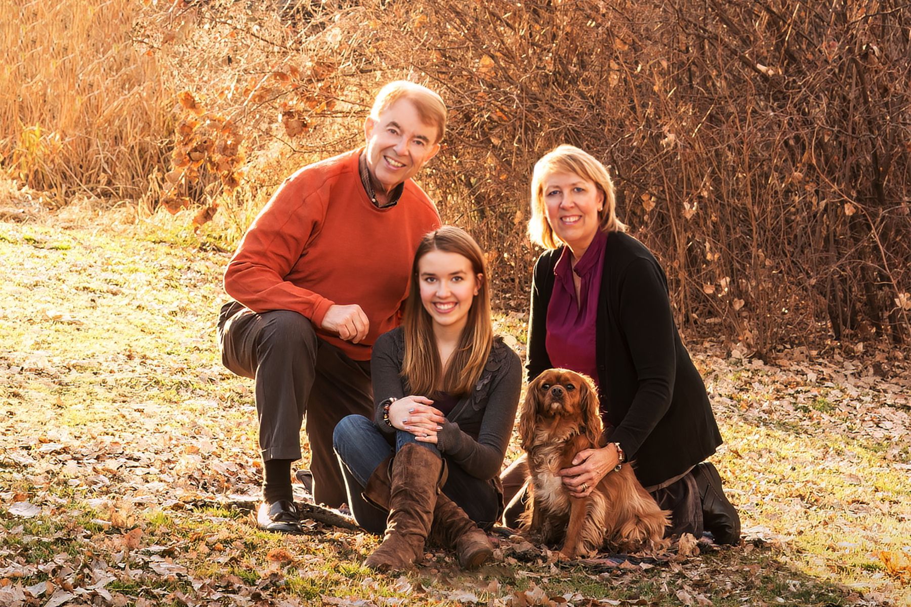 A family is posing for a picture with their dog.