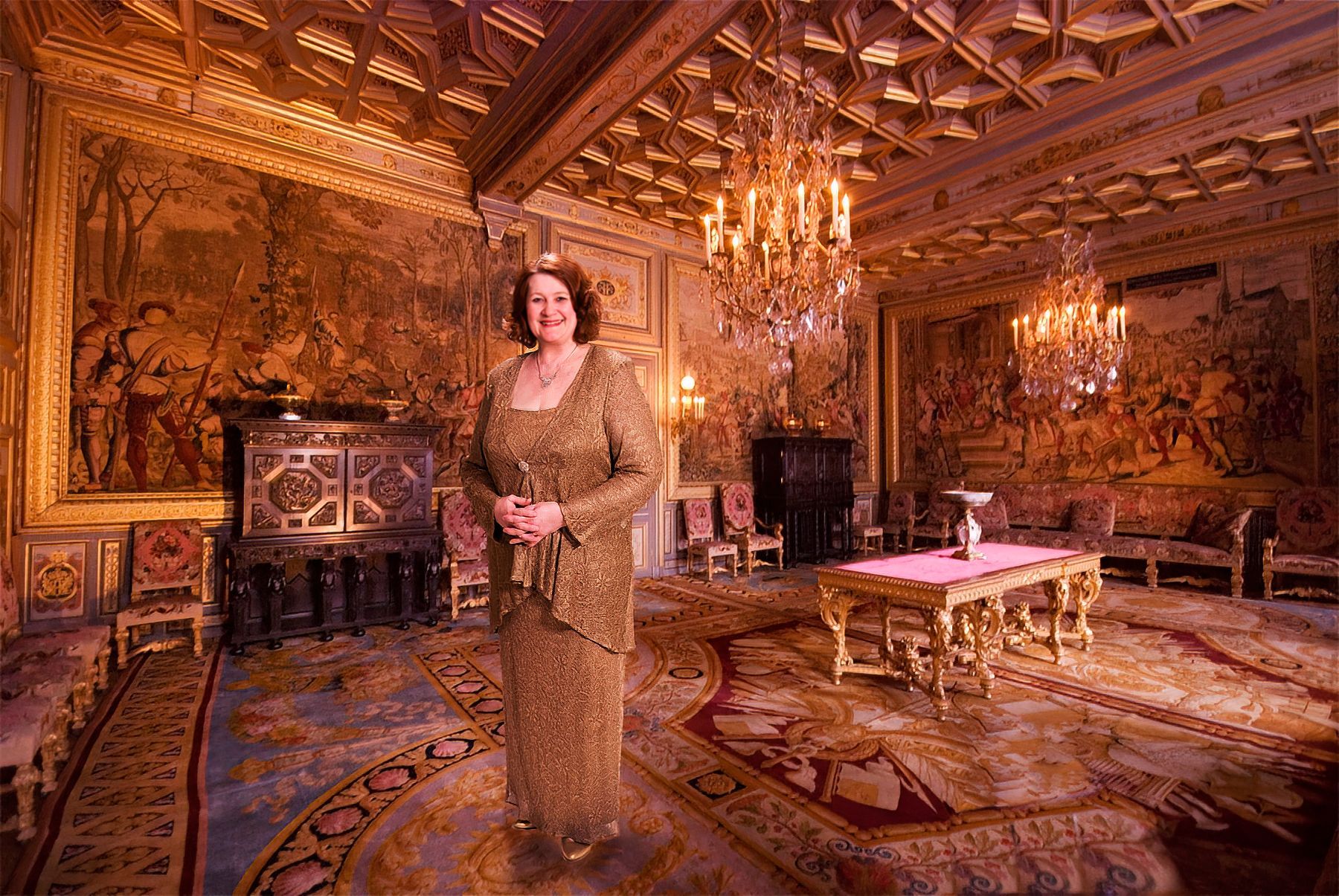 A woman in a gold dress is standing in a large room with a chandelier.