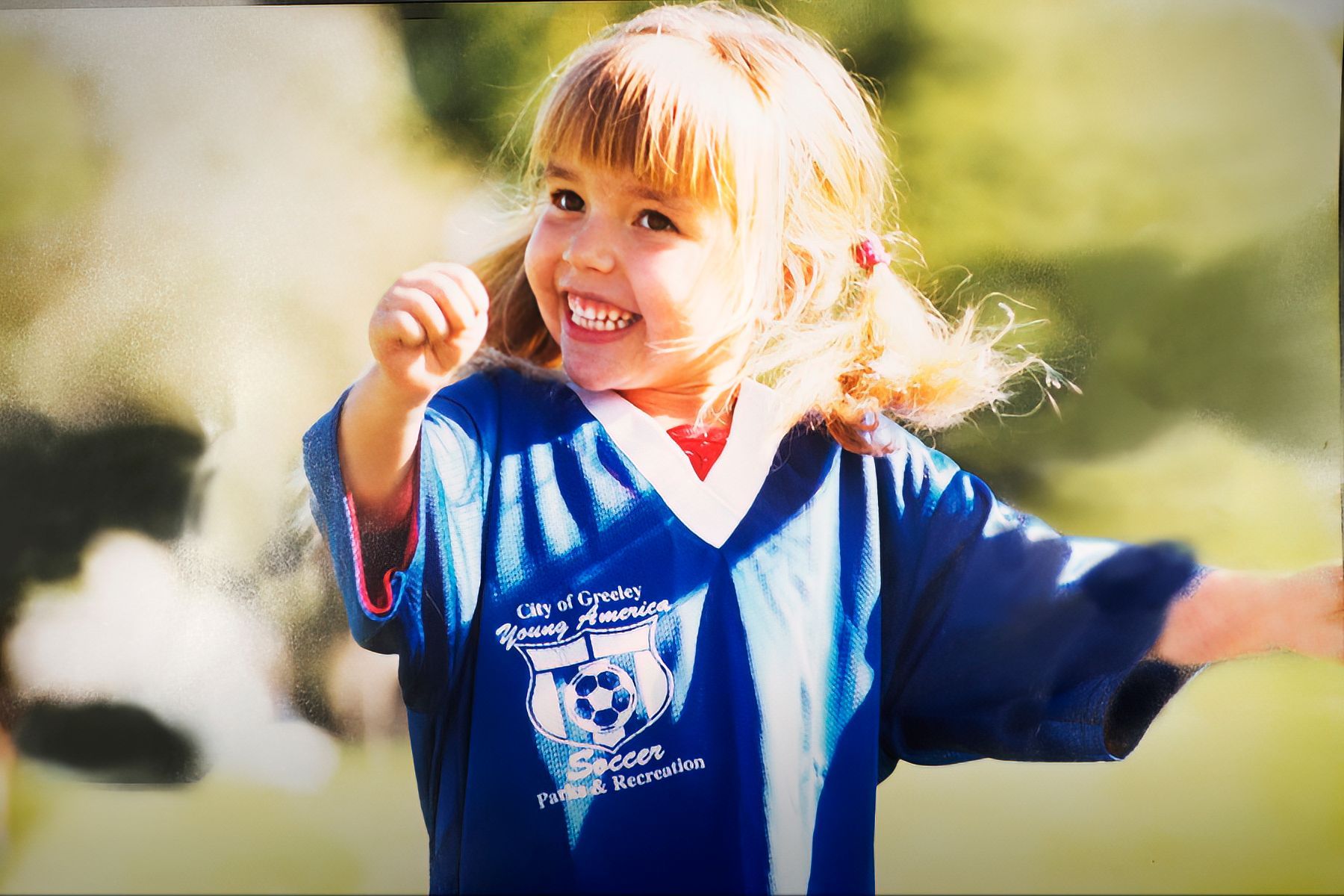 A little girl wearing a blue shirt with a soccer ball on it