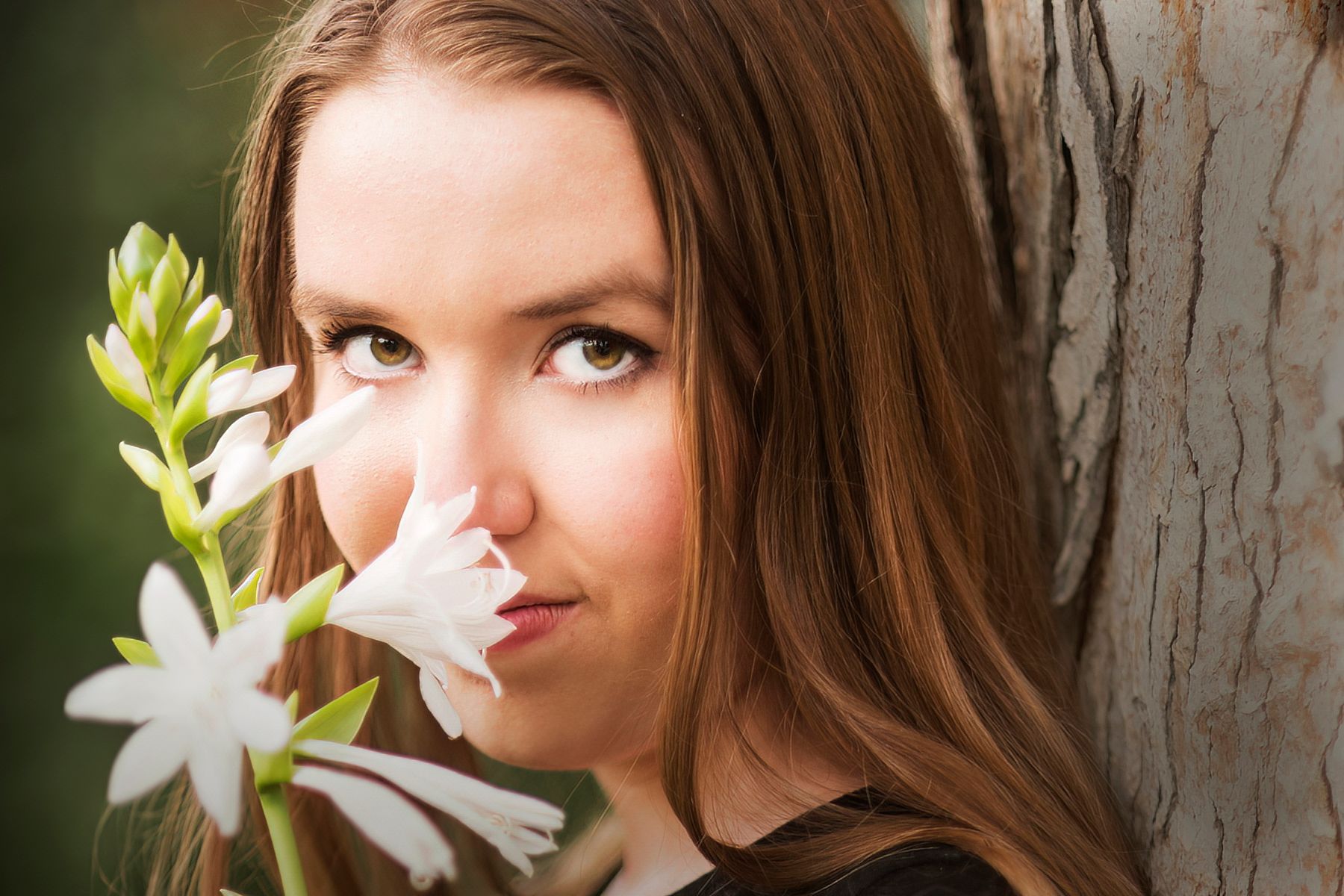 A woman is holding a white flower in front of her face.