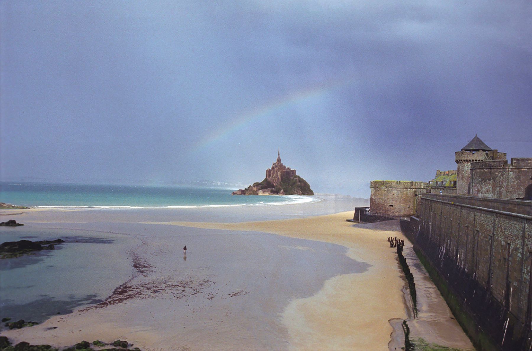 A beach with a castle in the background on a cloudy day