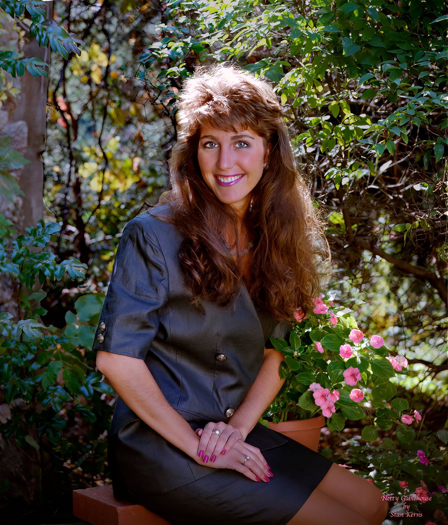 A woman in a black dress is sitting in front of flowers