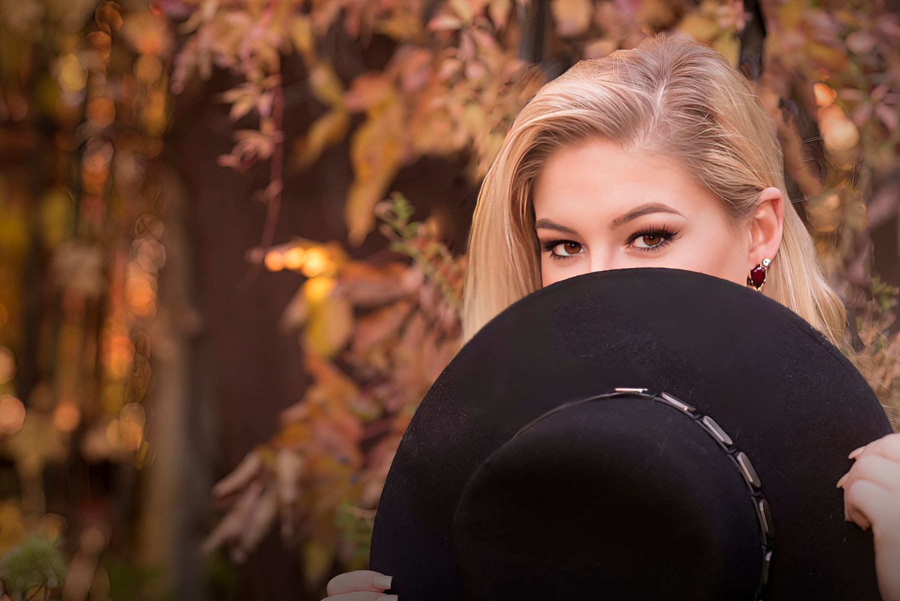 A woman is covering her face with a black hat.