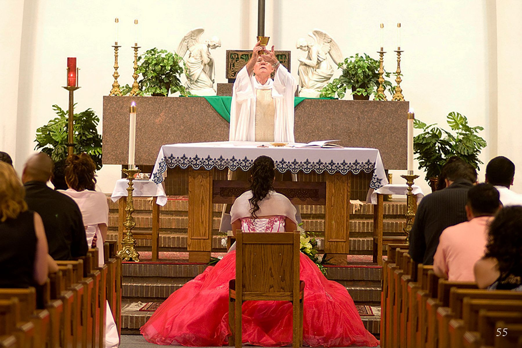 A woman in a red dress is sitting in front of an altar in a church.