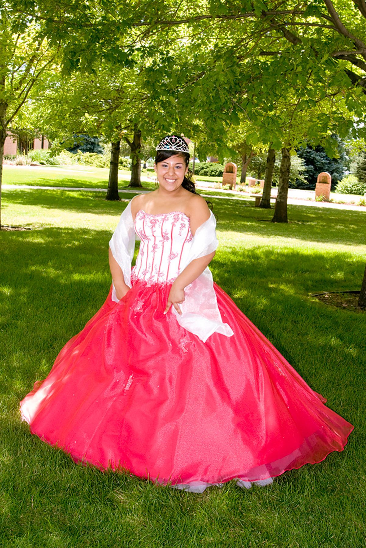 A woman in a red and white dress is standing in the grass.