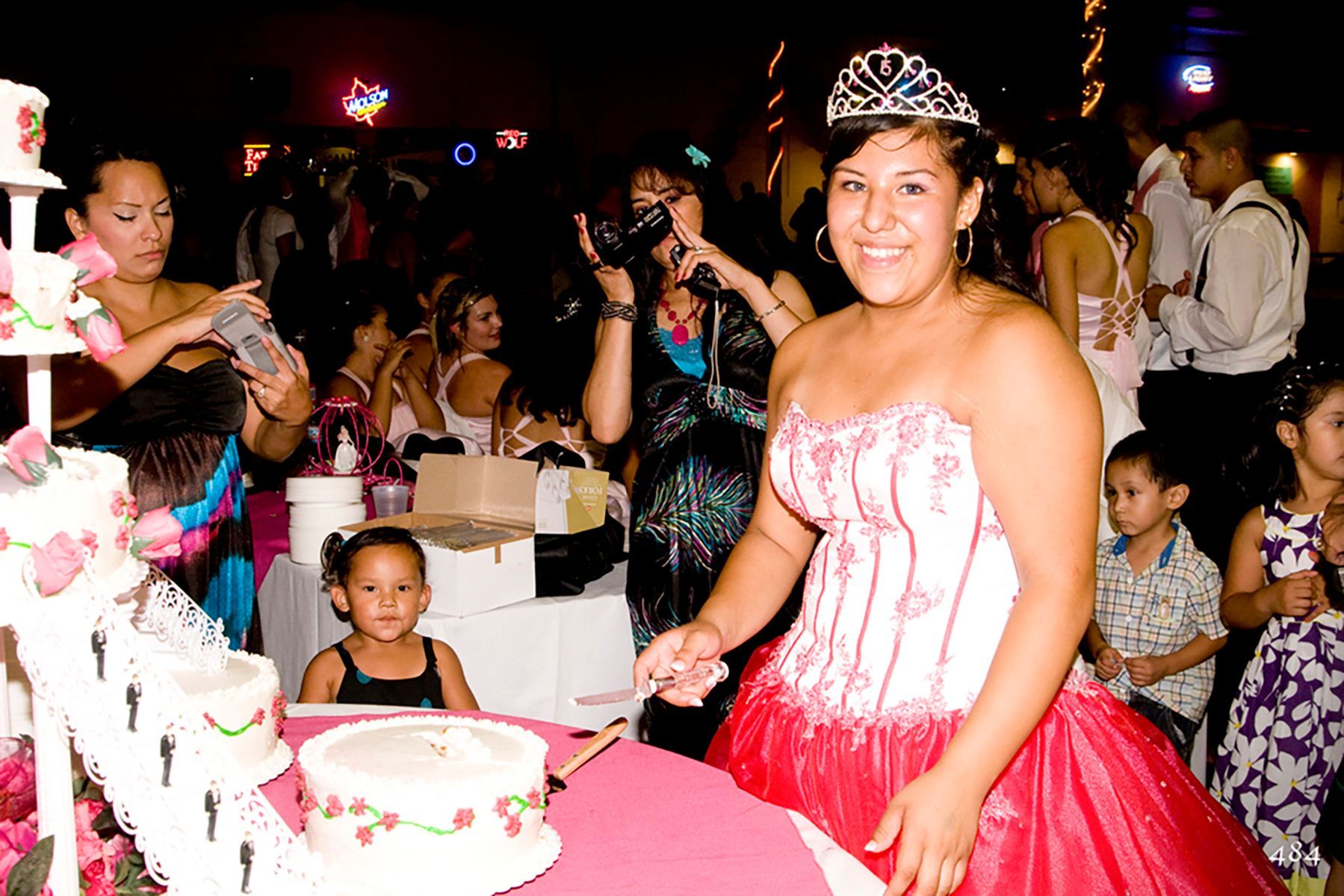 A woman in a red and white dress is cutting a cake