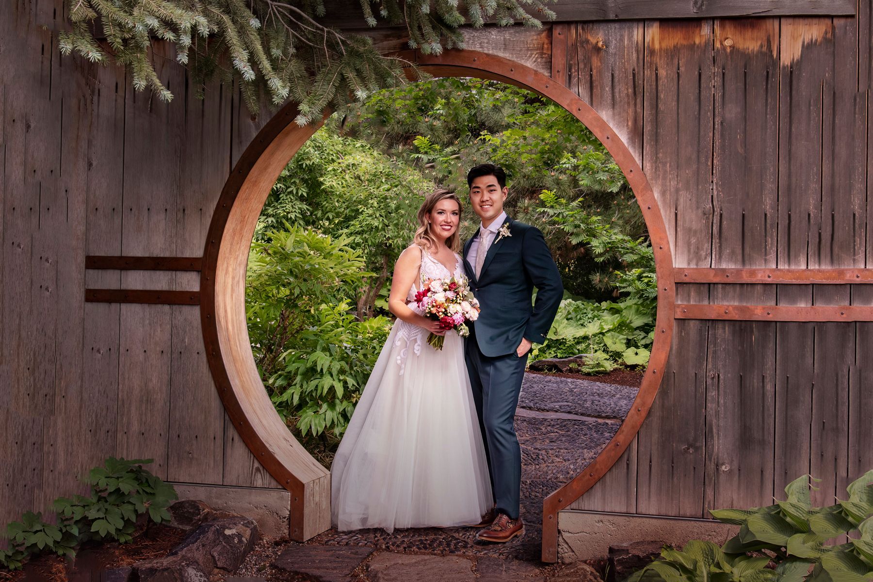 A bride and groom are posing for a picture in front of a wooden archway.
