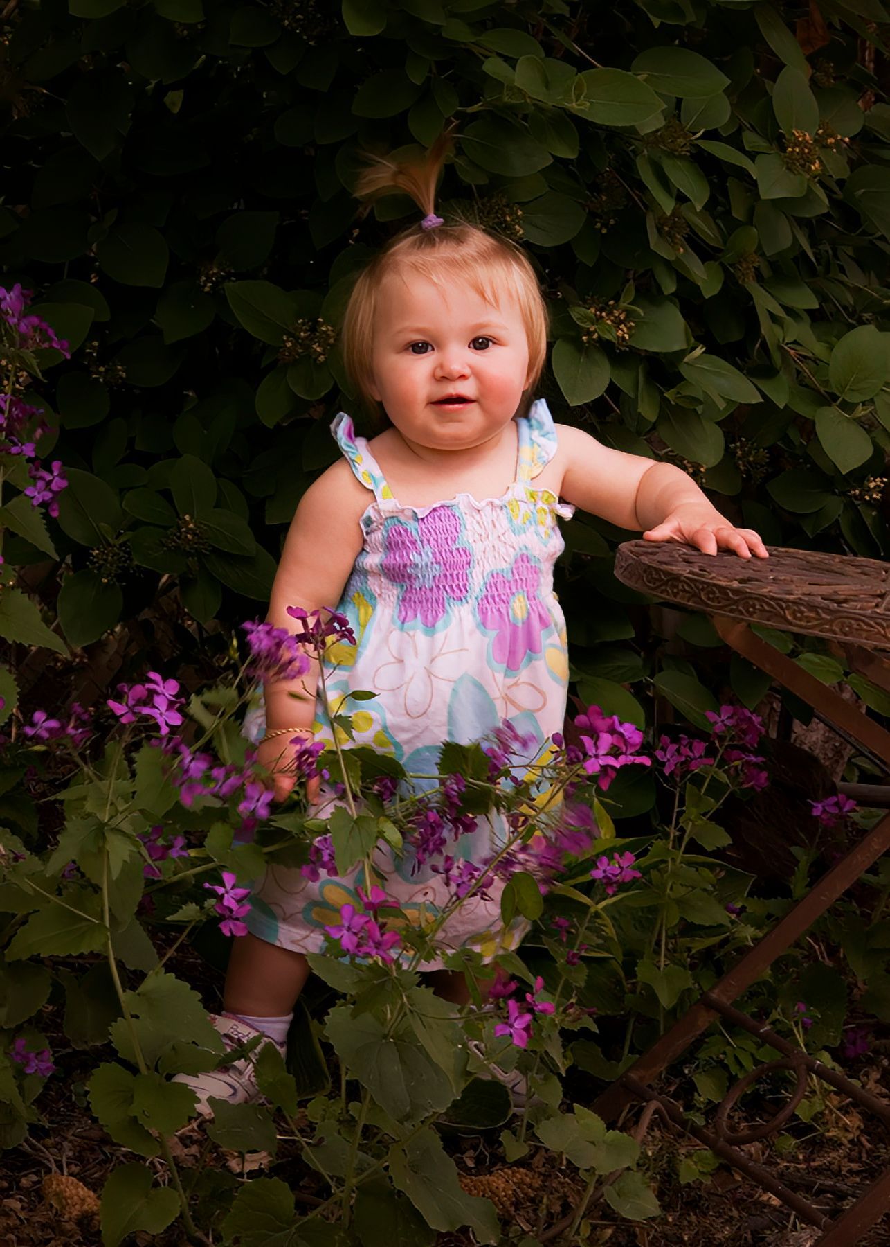 A little girl is standing in a garden surrounded by purple flowers.