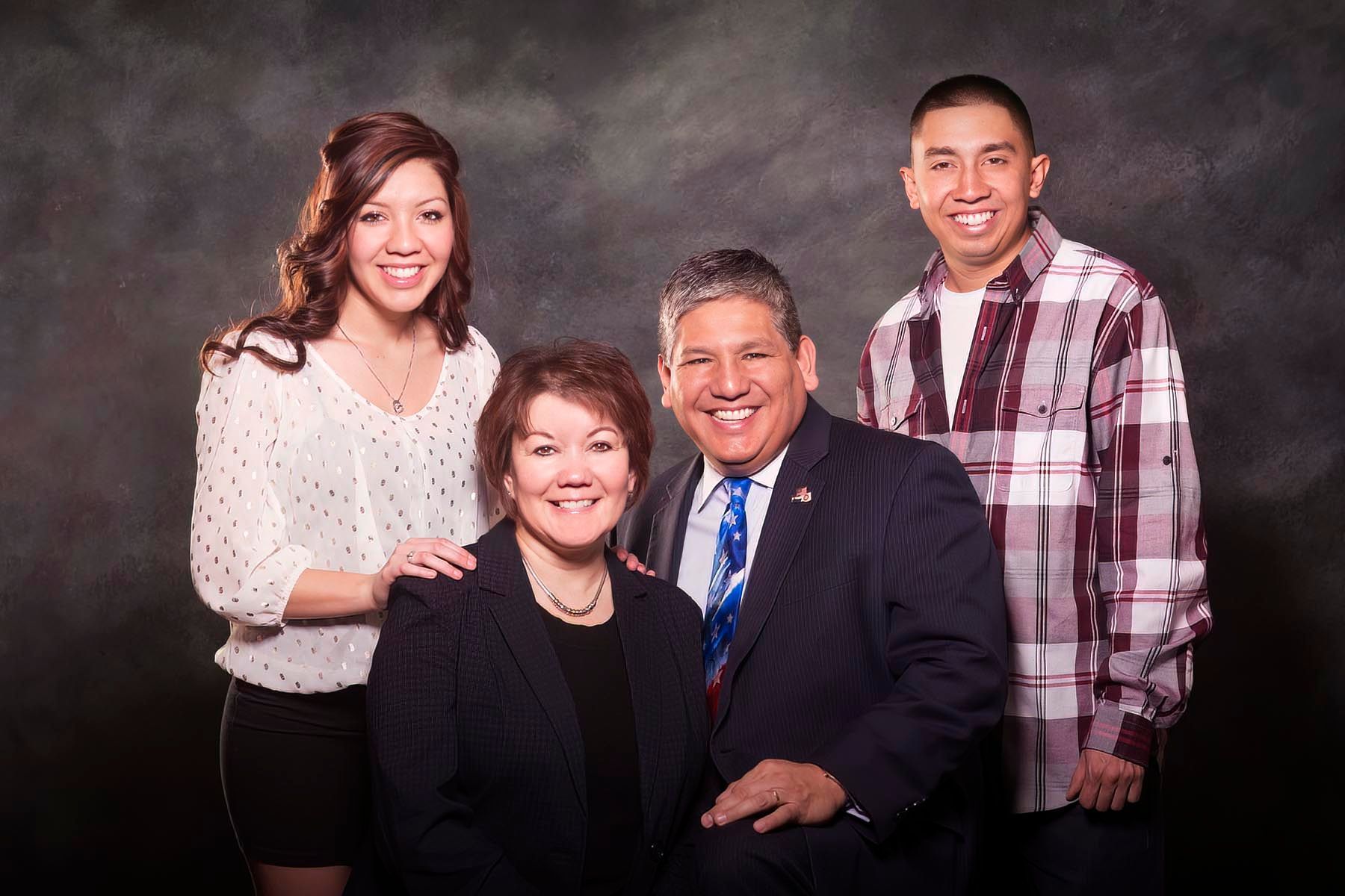 A family posing for a picture together in front of a black background.