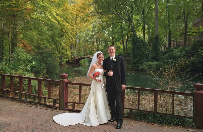 A bride and groom are posing for a picture on a bridge.