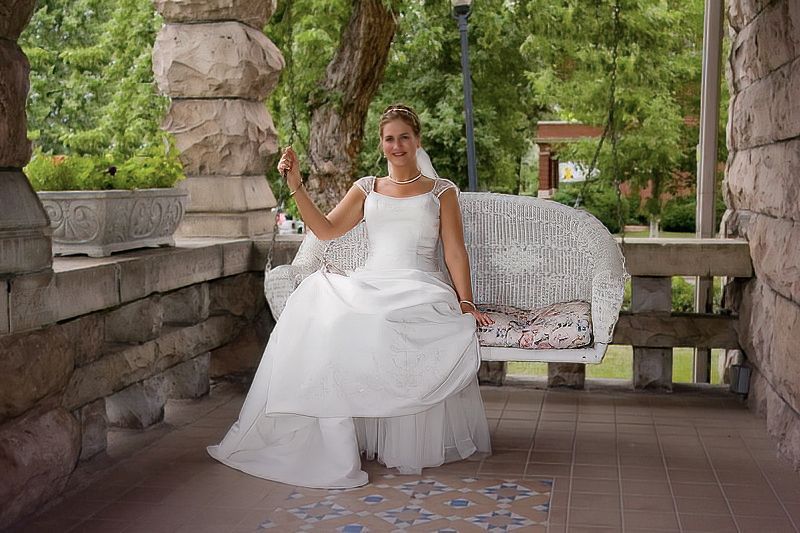 A bride in a wedding dress is sitting on a bench.
