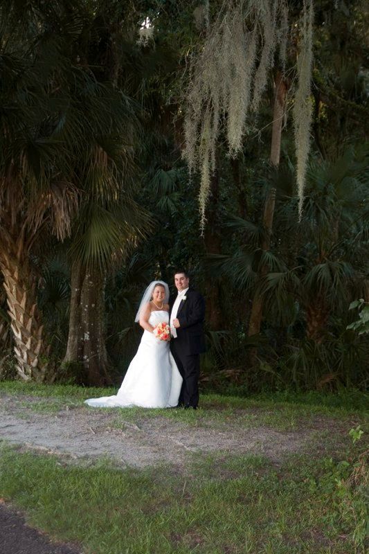 A bride and groom are posing for a picture in the woods.